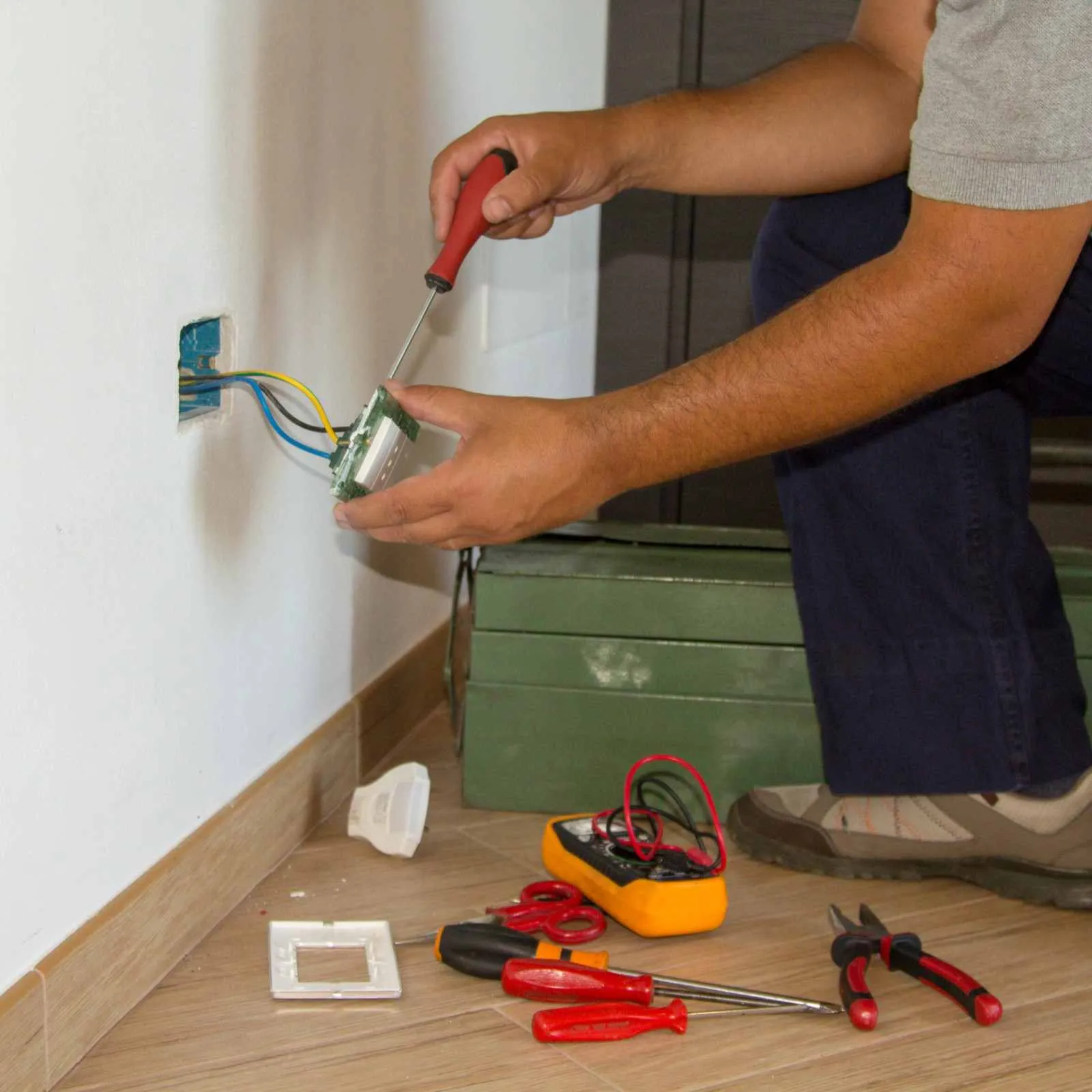 Electrician working on the wiring of a wall outlet