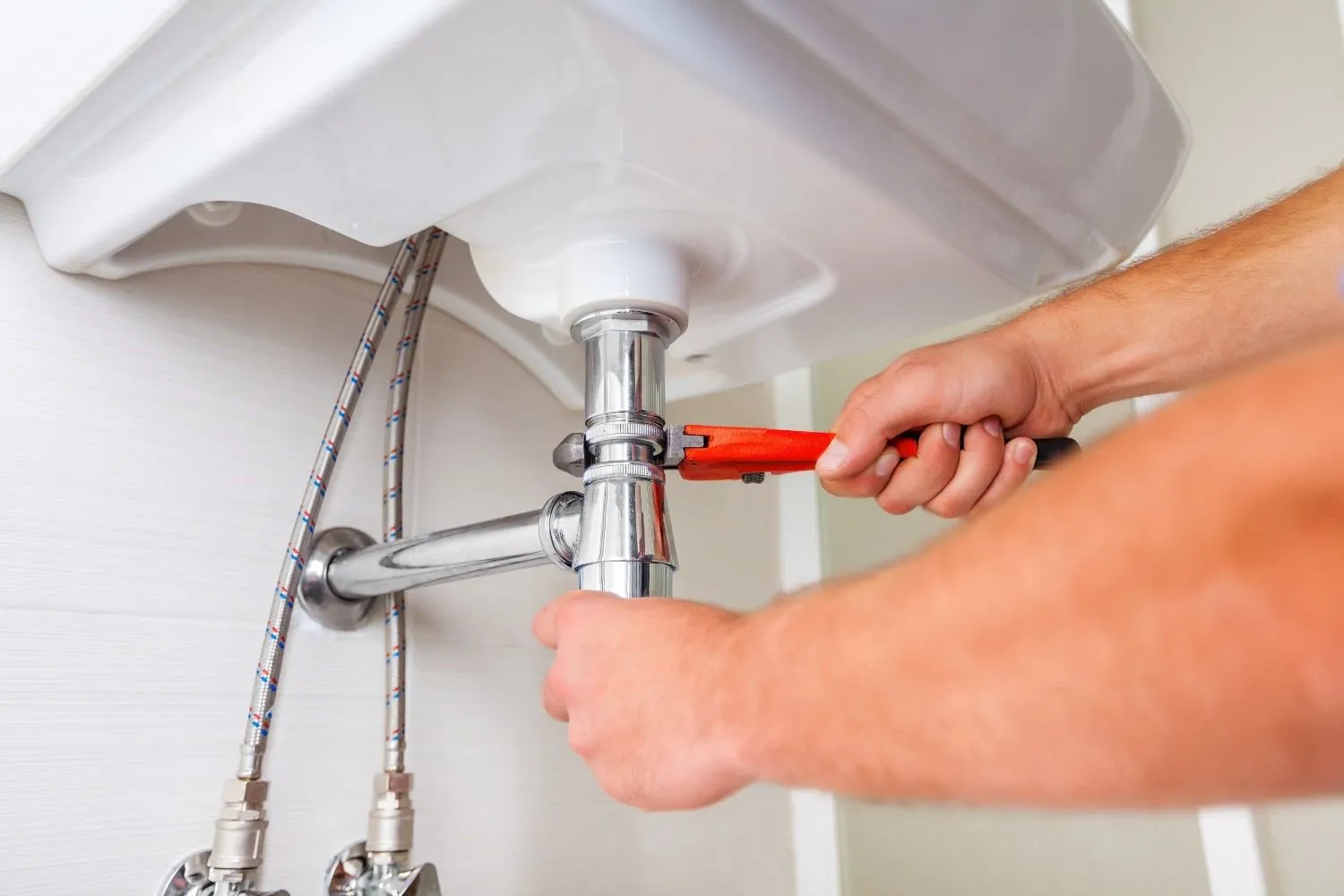 Plumber tightening the drain pipe under a bathroom sink